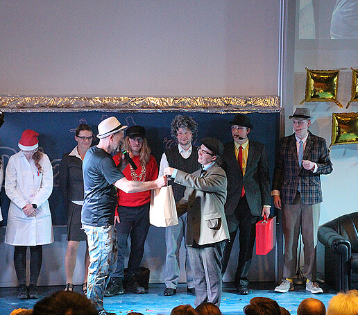 An actress hands Mr. Jeschke a bag.