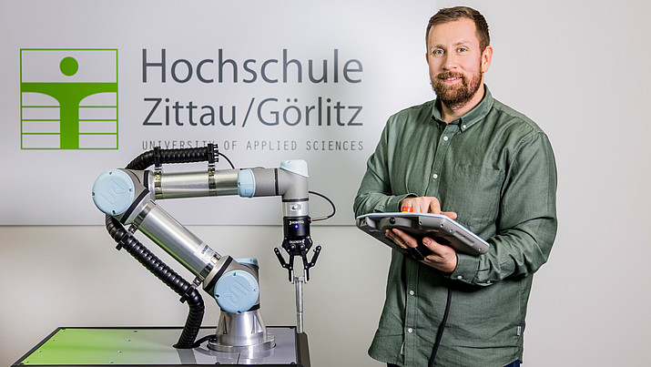 Ein Roboterarm wird von einem Mitarbeiter bedient.