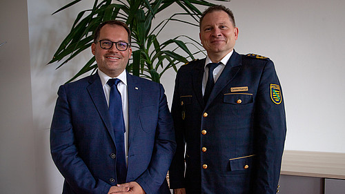 Der Rektor und Polizeipräsident Carsten Kaempf lächeln in die Kamera.