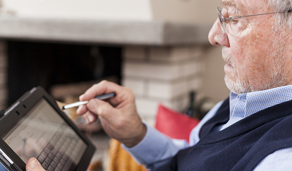 Älterer Mann nutzt einen Eingabestift auf einem Tablett. 