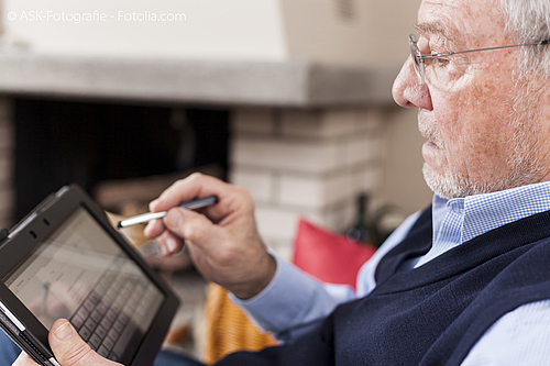 Älterer Mann nutzt einen Eingabestift auf einem Tablett. 