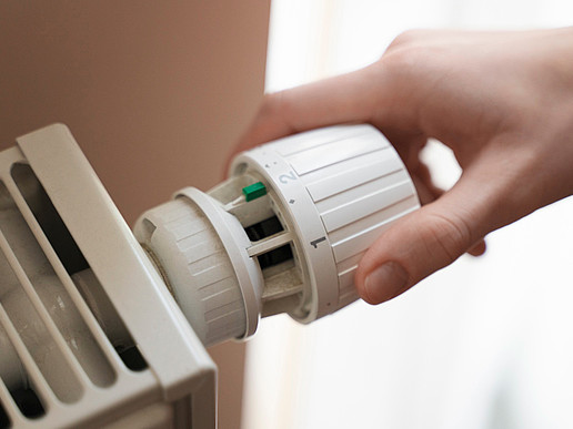 A hand screws on the control of a radiator.