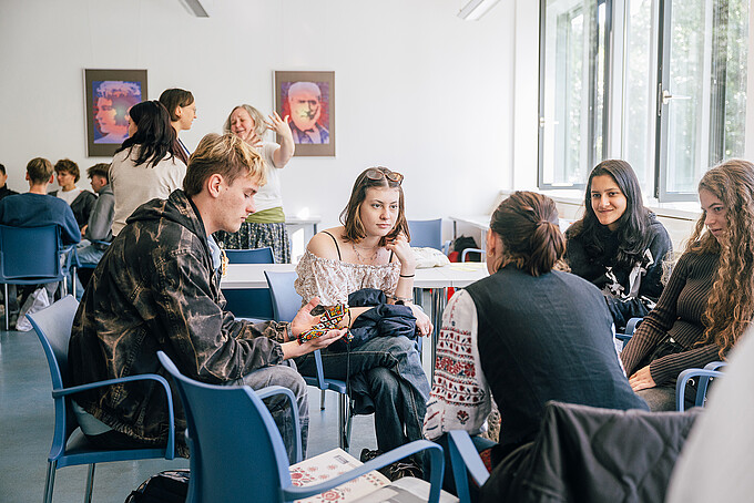 A group of students is sitting in a circle and discussing things with each other.