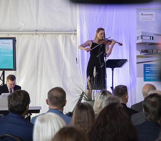 A violinist plays on stage in front of an audience.