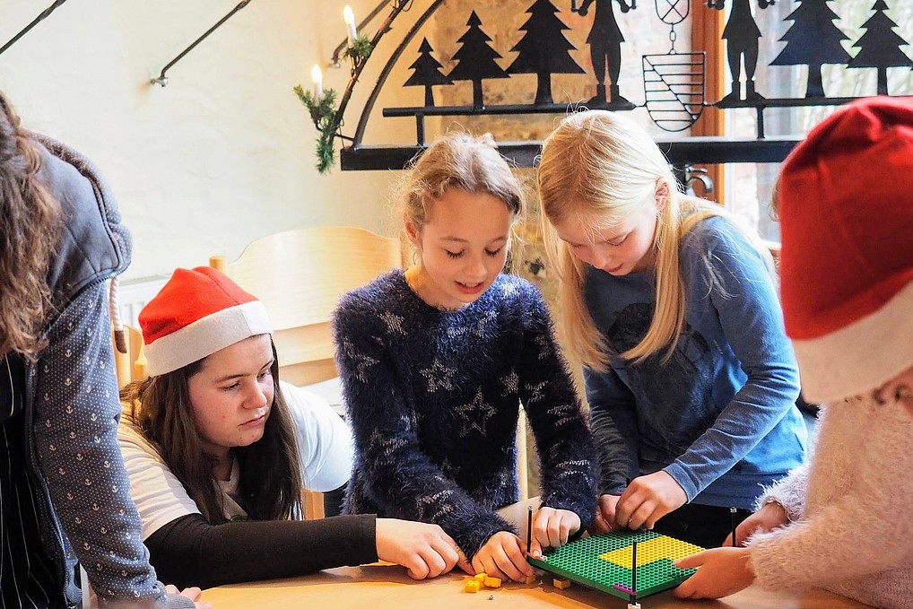 Kinder stehen am Tisch und spielen mit Lego