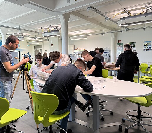 Schülerinnen und Schüler sitzen im School Lab an Tischen und experimentieren.