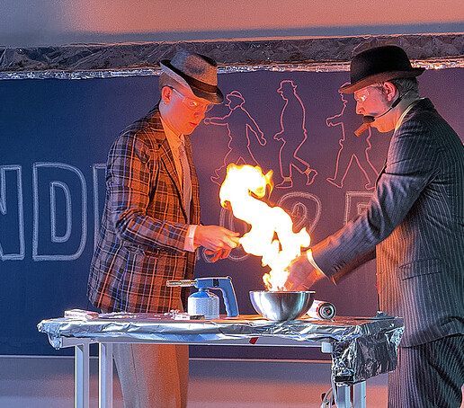 Two actors perform a fire experiment on stage.