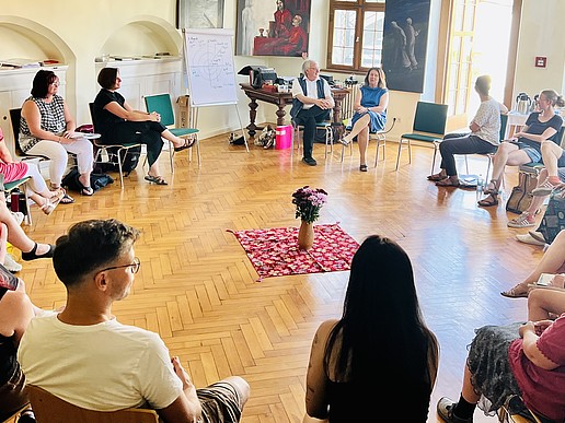 Participants in a systemic training course discuss in a circle of chairs.