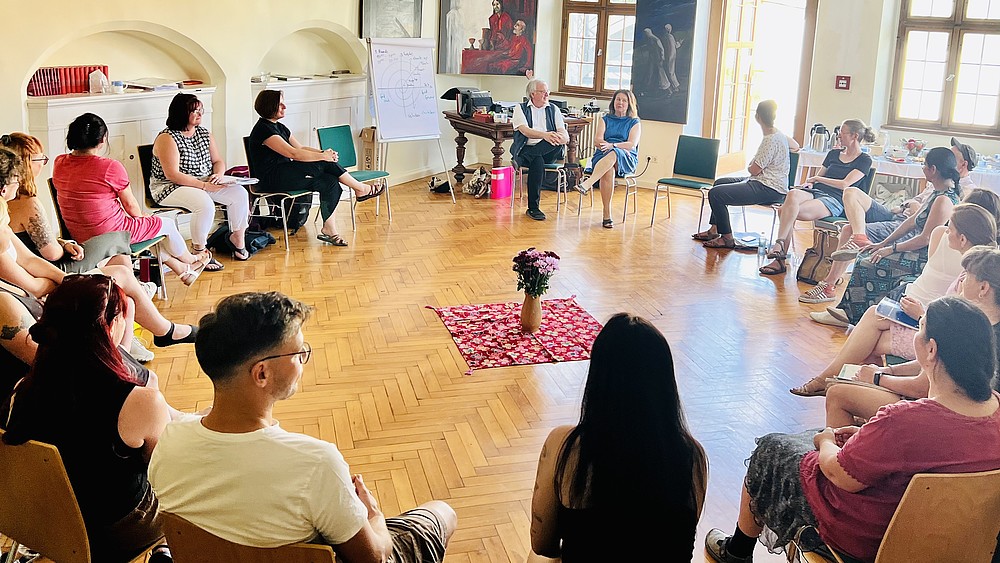 Participants in a systemic training course discuss in a circle of chairs.
