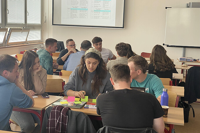 A group of students sits at the table and works something out.