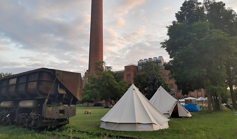 Foto: HSZG Camp mit Zelten im Freien vor den Fabrikgebäuden in Knappenrode