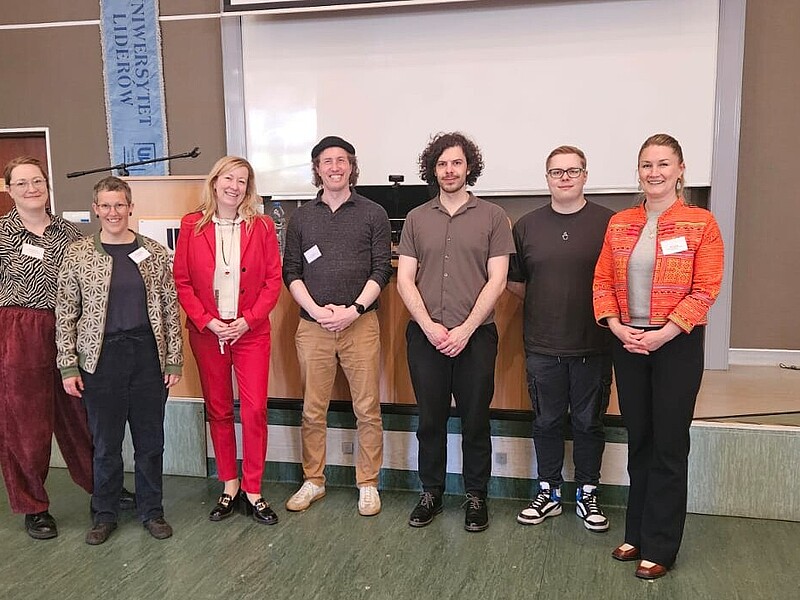 Prorektorin Keil, Inna Hauf und Teilnehmende der ACC-Konferenz stehen zum Gruppenbild nebeneinander vor einer Bühne.