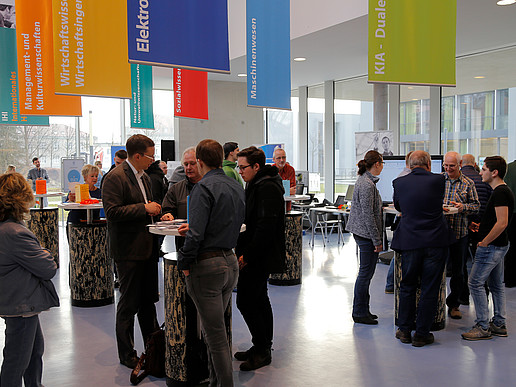 Studieninteressierte und Hochschulangehörige stehen an Beratungstischen im Foyer des Peter-Dierich-Hauses in Zittau.