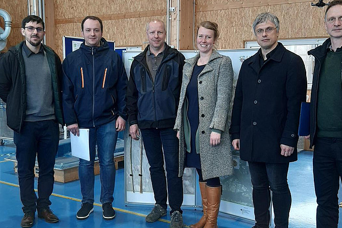 HSZG and Härtwig Maschinenbau GmbH employees stand next to each other for the group photo in the Landerhalle and smile into the camera.