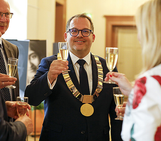 The rector raises his champagne glass surrounded by guests.