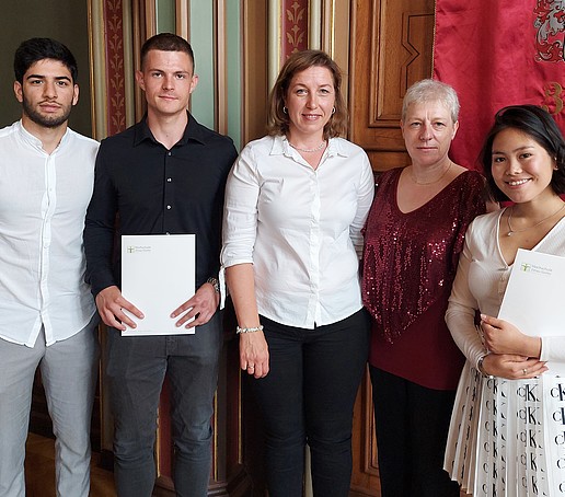 A graduate and graduates stand together with supervisors from the preparatory college in the town hall of Zittau town hall.