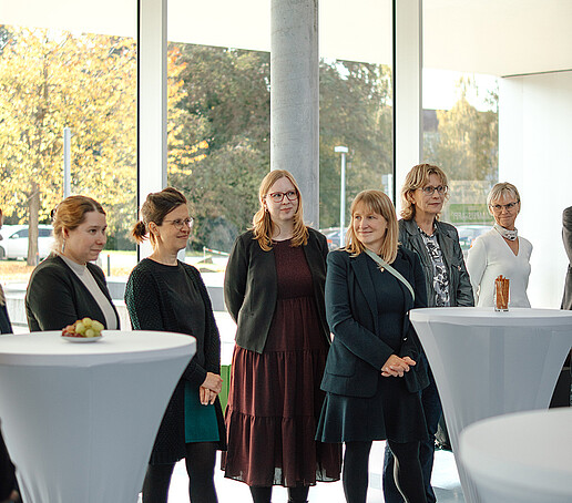 Guests at the event stand around bar tables.