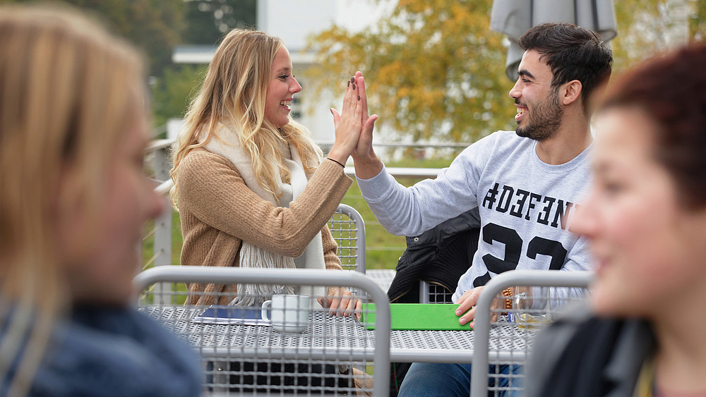 Studentin und Student klatschen sich ab.