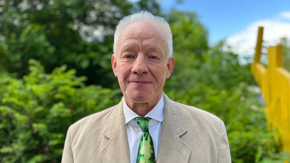 Prof. Kästner stands outside on the Görlitz campus in a suit and smiles at the camera.