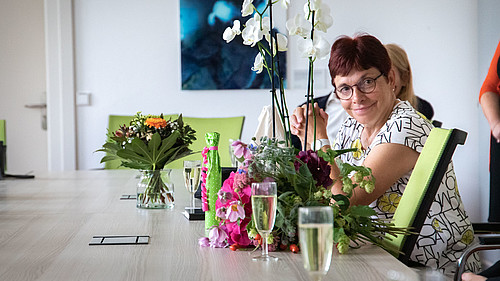 Die Kanzlerin der HSZG sitzt an einem Tisch, ist umringt von Gästen und Geschenken und lächelt in die Kamera.