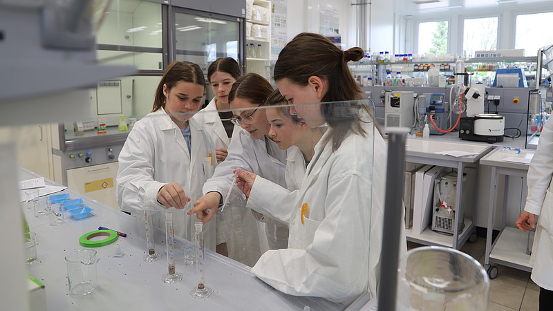 Schülerinnen im Chemielabor arbeiten mit Messbechern.