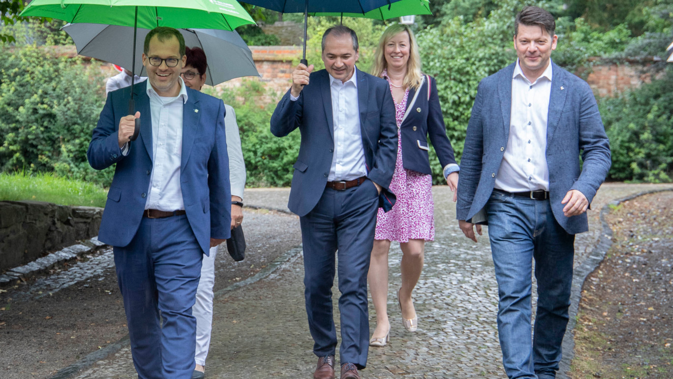 3 men and 2 women with umbrellas on a walk