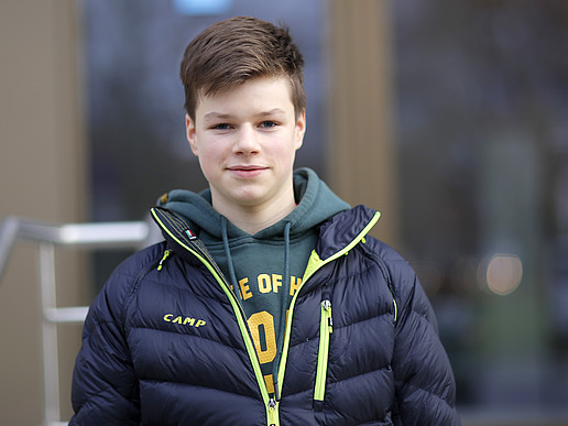 Justus stands in front of building Z 1 and smiles at the camera.