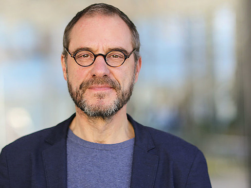 Prof. Kollmorgen in a blue sack and glasses smiles into the camera.