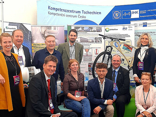 Representatives of Life and Technology and Saxon companies pose in front of an IHK Dresden stand.