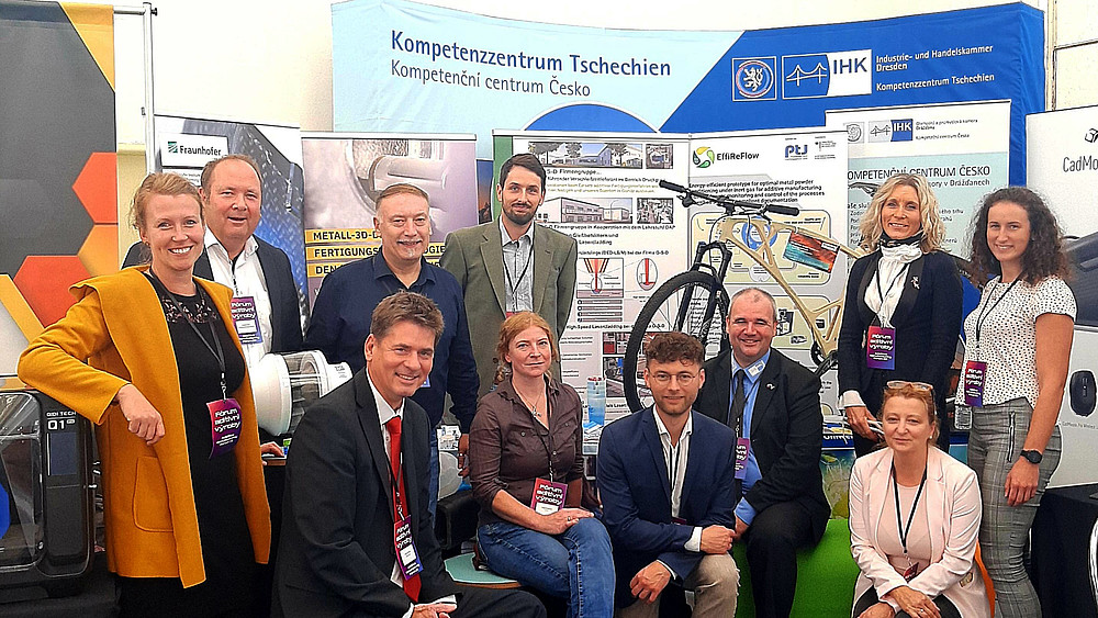Representatives of Life and Technology and Saxon companies pose in front of an IHK Dresden stand.