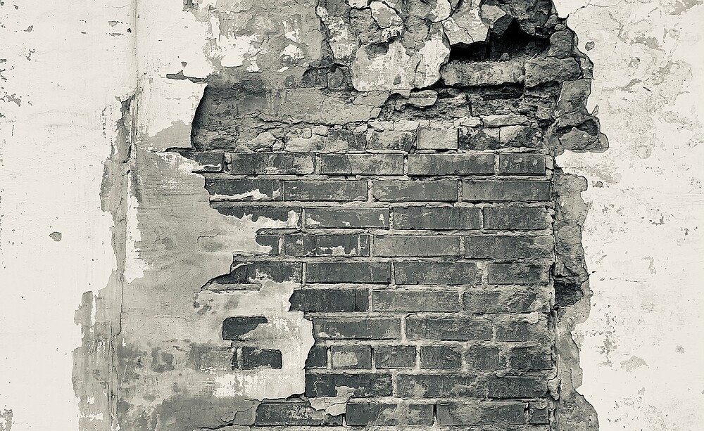 Crumbling plaster in front of a brick wall