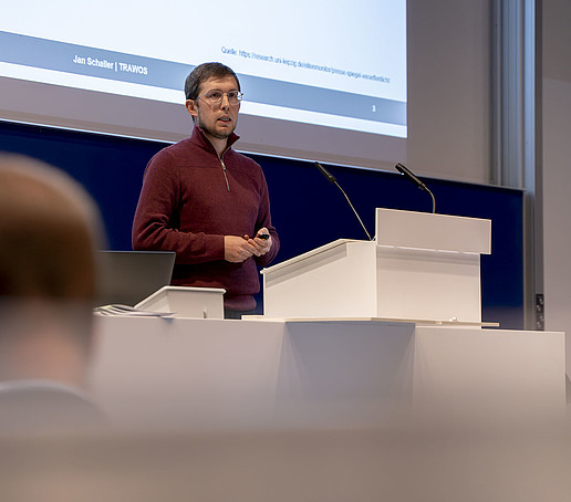 Jan Schaller stands at a desk in the lecture hall.