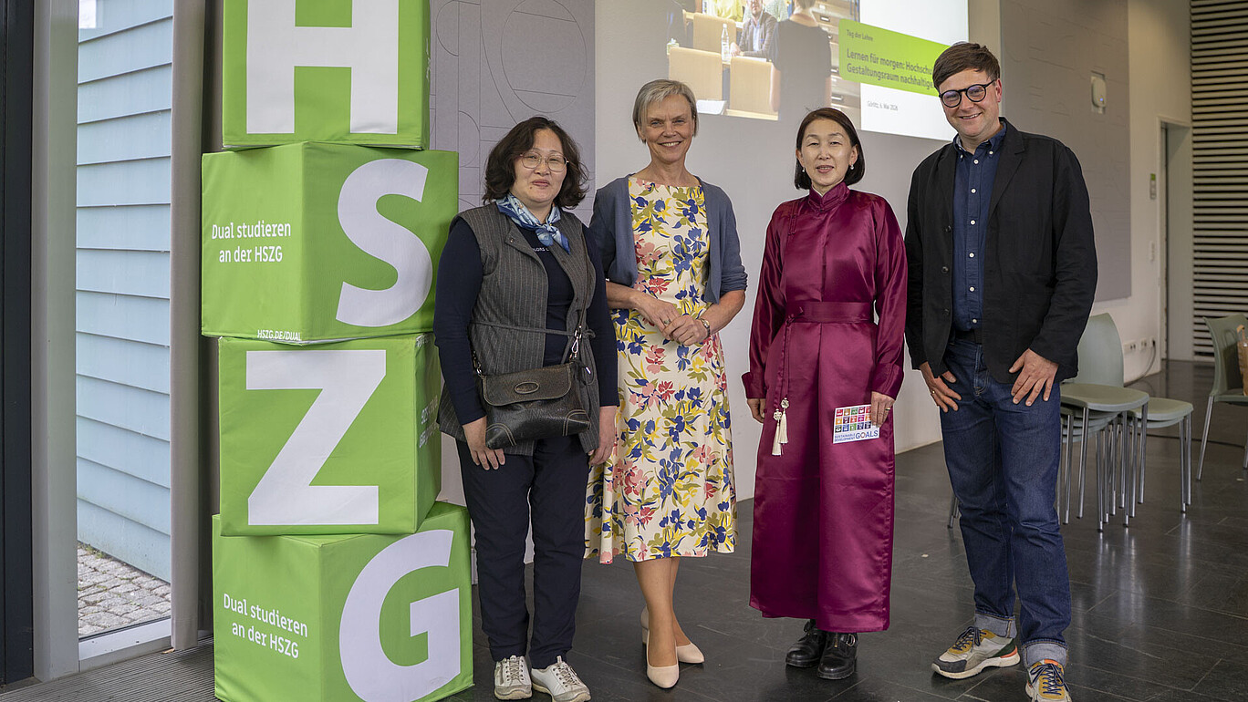 Internationale Gäste aus der Mongolei im Gespräch mit Professorin Małgorzata Maćkowiak, Prorektorin Bildung und Nachhaltigkeit, und Daniel Winkler, Referent Hochschuldidaktik stehen nebeneinander in der Aula zum Gruppenbild.