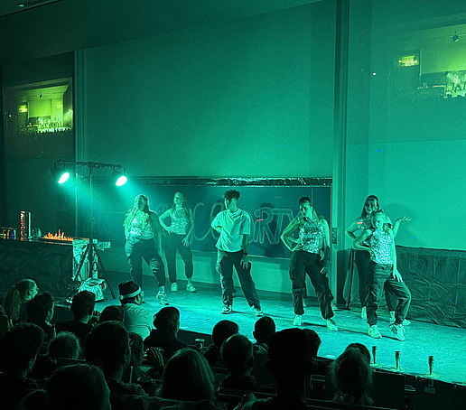 A dance group dances on the podium in the green light.
