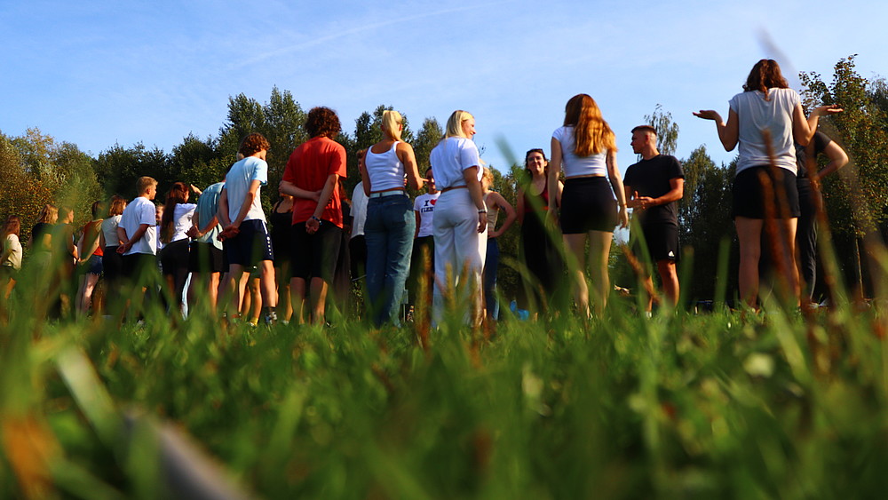 Students stand on a meadow and look at each other.