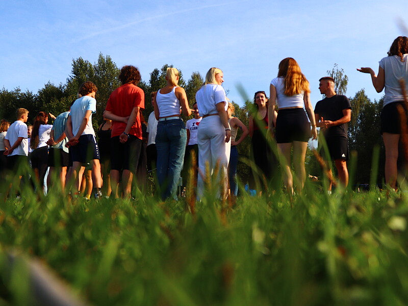 Students stand on a meadow and look at each other.