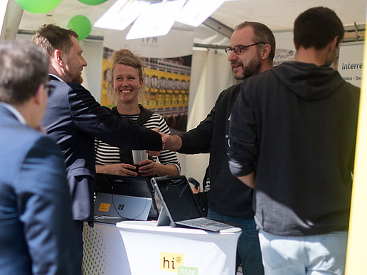 Der Ministerpräsident und Prorektor schütteln sich Hände am HSZG-Stand.