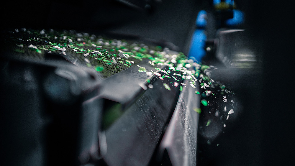 Green plastic particles fly out of a machine