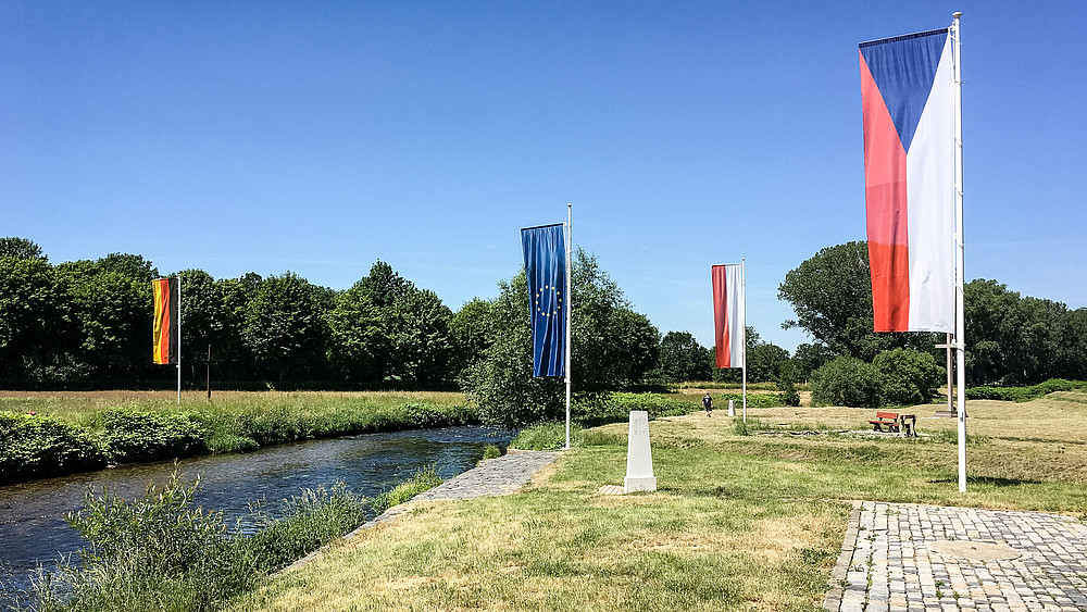 Die deutsche, europäische, polnische und tschechische Flagge unter blauem Himmel am Dreiländerpunkt