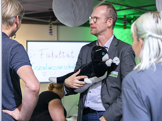 GAT Institute Director Prof. Andreas Hoff holds the JustoCat at the trade fair stand at the INSIDERTREFF in Löbau.