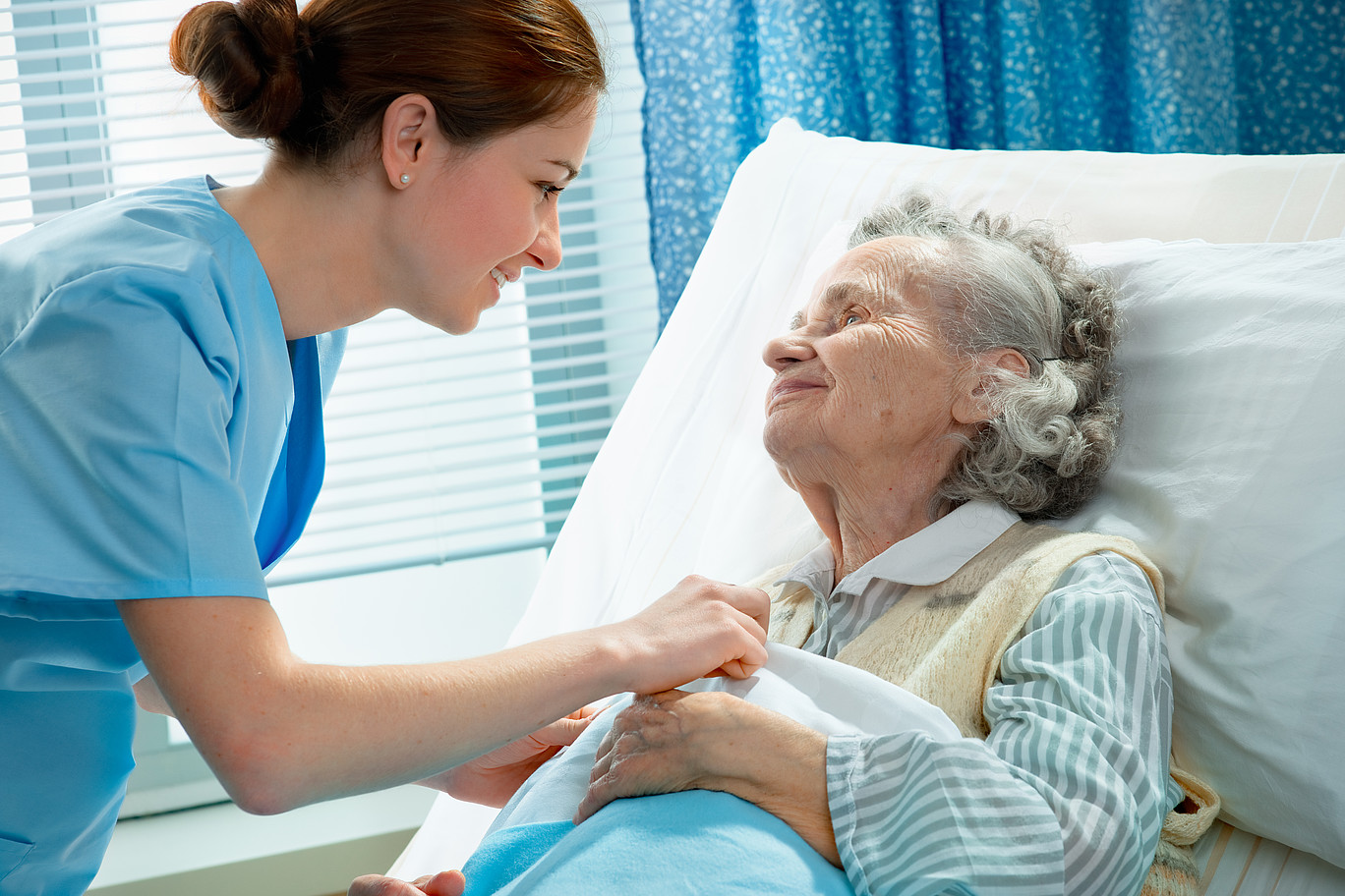 elderly woman in bed, with nurse