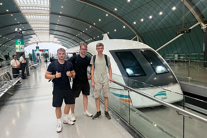 Three students stand next to the Transrapid train that will take them through Shanghai.