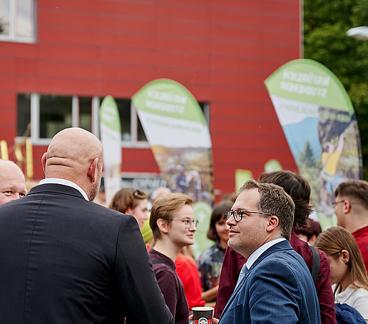 Rektor unterhält sich mit Professor auf dem Campus.