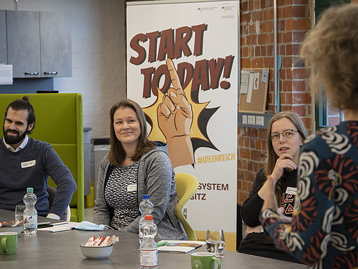 A group of employees sit at a table in Celsiuz and listen to a lecturer.