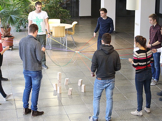 Students stand in a circle and hold strings in their hands.