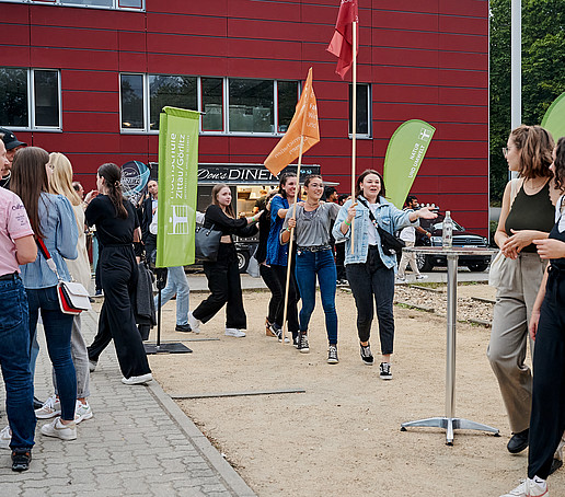 Studierende machen eine Polonaise auf dem Campus.