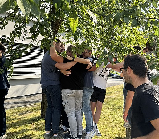Students stand around a tree.