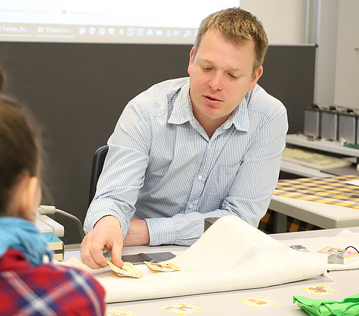 An employee places cards on the table in front of girls watching with interest.
