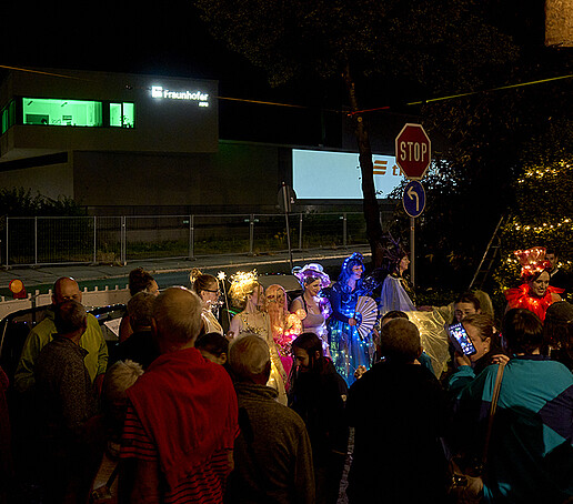 Visitors stand around a group with bright costumes on the city ring road.