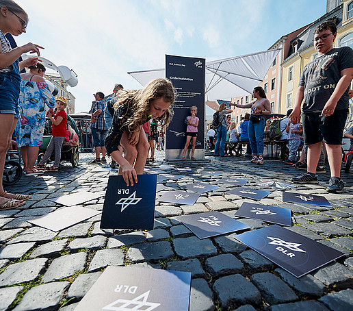 Children lay DLR cards on paving stones.